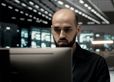 Homem em frente ao computador trabalhando num ambiente de data center